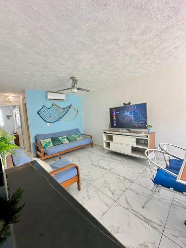 a living room with a couch and a tv at Departamento Acapulco frente a la playa in Acapulco