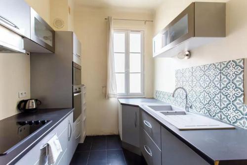 une petite cuisine avec un évier et une fenêtre dans l'établissement Charmant appartement avec terrasse en plein cœur de Nice à deux pas de la mer !, à Nice