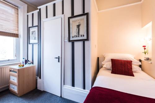 a small bedroom with a bed and a window at Paskins Town House in Brighton & Hove