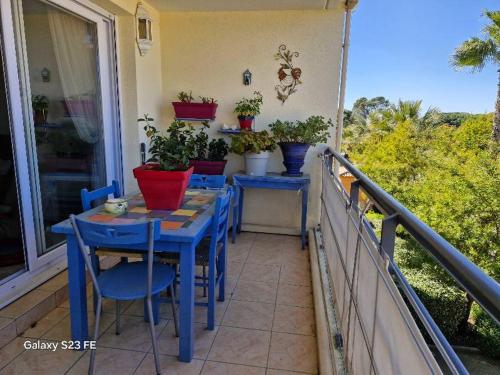 un porche avec des tables et des chaises bleues et des plantes en pot dans l'établissement Villa Florentine Fréjus, à Fréjus