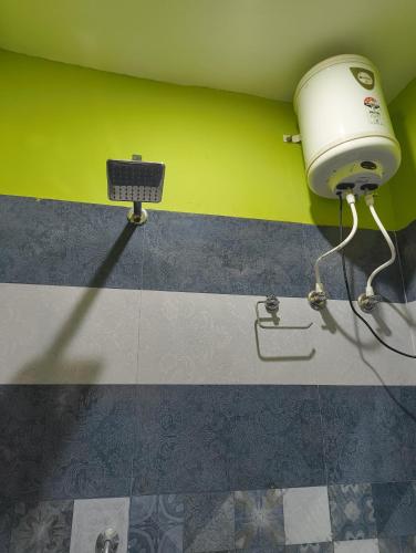 a bathroom with a hair dryer and a green wall at heights of dhanaulti a 360 view guest house in Dhanaulti