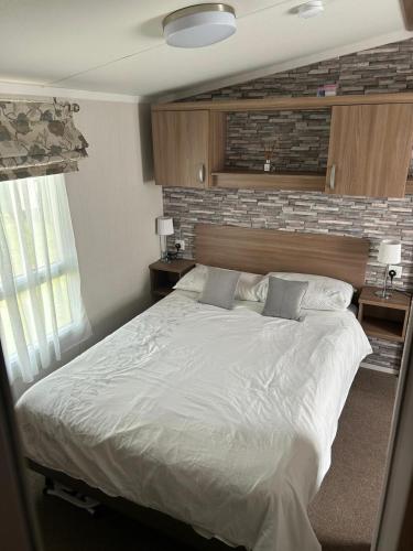 a bedroom with a large white bed and a brick wall at Molly's Haven in Milford on Sea