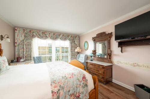 a bedroom with a bed and a dresser and a window at Boardwalk Plaza Hotel in Rehoboth Beach