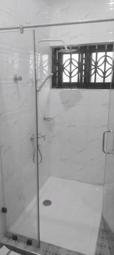 a glass shower in a bathroom with a window at Michael’s Apartment Complex in Accra