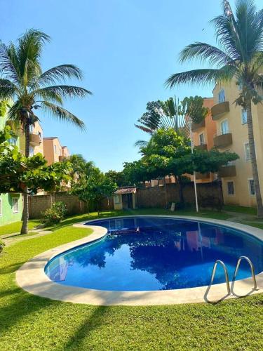 a swimming pool in a yard with palm trees at Departamento planta baja en Acapulco Diamante in Acapulco