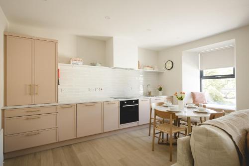 a kitchen with white cabinets and a table with chairs at The Old Schoolhouse - Castle View in Donegal