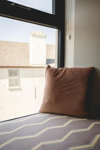 a pillow sitting on a bed in front of a window at The Old Schoolhouse - Castle View in Donegal