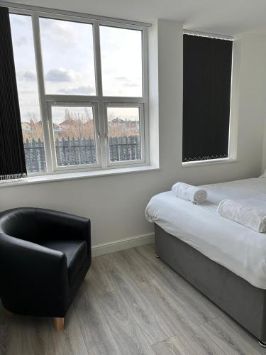 a bedroom with a bed and a chair and windows at Train Station Aparthotel - Free Wifi, Free Parking in Scunthorpe