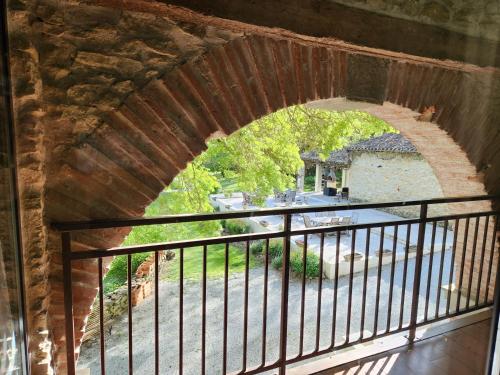 an archway in a brick wall with a balcony at Le Clos Sainte Marie - Caune in Cenne-Monestiès
