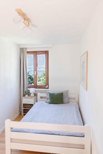 a white bedroom with a bed and a window at BnB Casa Bellavista Sant Abbondio 6577 Ranzo in Gerra