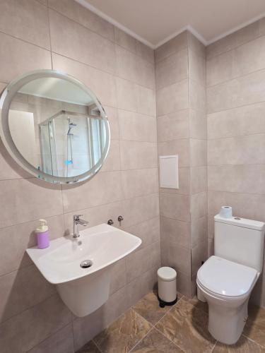 a bathroom with a sink and a toilet and a mirror at ATEA PERLA apartments in Kavarna