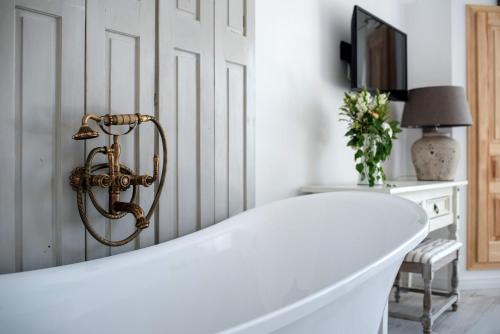 a white bath tub in a white room with a lamp at Hazai Provence in Kapolcs