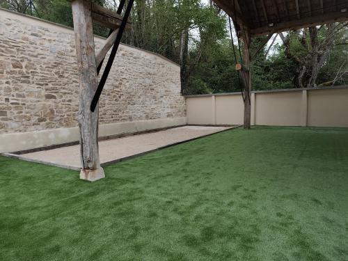 a patio with a green lawn with a brick wall at Le Bacchus in Chablis