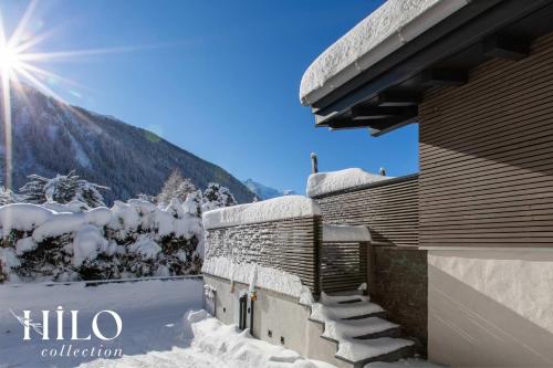 une maison enneigée avec le soleil en arrière-plan dans l'établissement A great chalet for 4 people with Jacuzzi, à Chamonix-Mont-Blanc