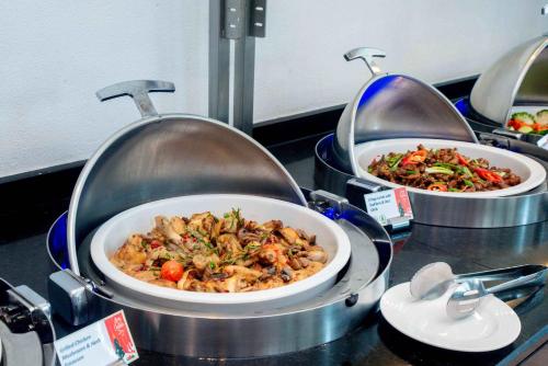 a buffet with three dishes of food on a table at Holiday Inn Abu Dhabi by IHG in Abu Dhabi