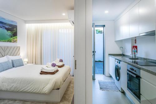 a white bedroom with a bed and a kitchen at GuestReady - Passal Guesthouse in Ponta Delgada