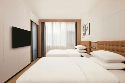 a hotel room with three beds and a flat screen tv at Four Points by Sheraton Kunming Dongfeng Square in Kunming