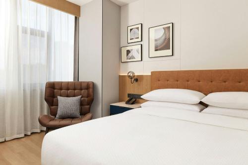 a bedroom with a large bed and a chair at Four Points by Sheraton Kunming Dongfeng Square in Kunming