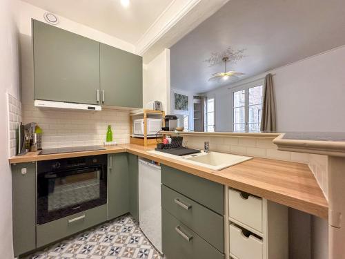 une cuisine avec des armoires vertes et un évier dans l'établissement Le Foyer Chartrain, à Chartres