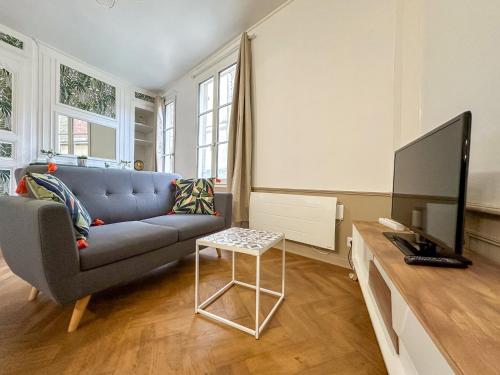 un salon avec un canapé bleu et une télévision dans l'établissement Le Foyer Chartrain, à Chartres