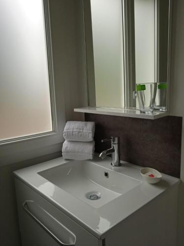 une salle de bain avec un lavabo blanc et un miroir dans l'établissement Les Cabanes du Lac, à Vandré