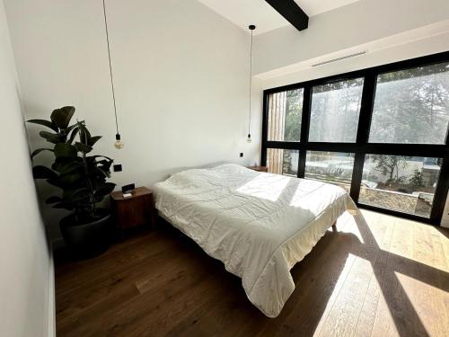 a bedroom with a bed and a large window at Maison bord de mer Anglet in Anglet