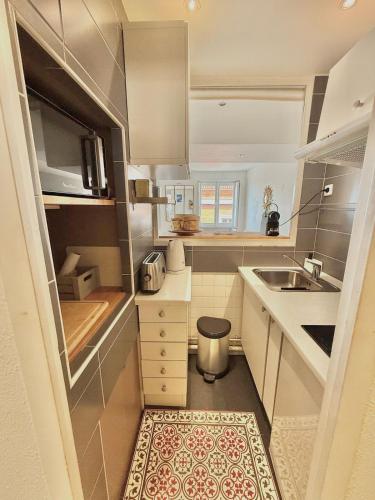 une petite cuisine avec des armoires blanches et un évier dans l'établissement Capitole by Yumē, à Toulouse