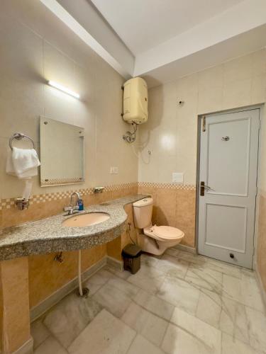 a bathroom with a sink and a toilet and a mirror at Atreya Boutique Cottage Serene Villa Near Ram Jhula in Rishīkesh