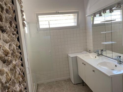 a white bathroom with a sink and a mirror at Maison 10 personnes 250m plage in Canet-en-Roussillon