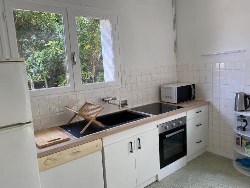 une cuisine avec un évier et un micro-ondes dans l'établissement Maison 10 personnes 250m plage, à Canet