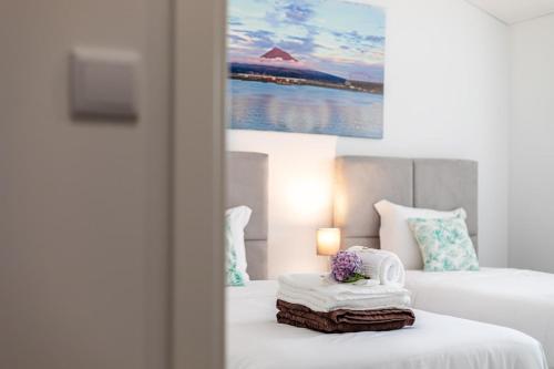 a hotel room with two beds with towels and a painting at GuestReady - Passal Guesthouse in Ponta Delgada