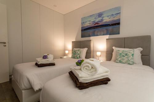 two beds with towels on them in a bedroom at GuestReady - Passal Guesthouse in Ponta Delgada