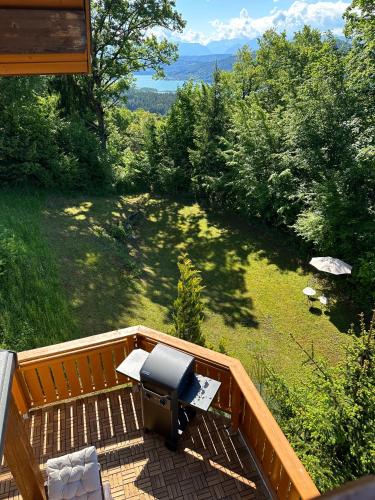 an outdoor patio with a grill and chairs on a deck at Villa Sara - Wörtherseeblick, Sauna, Panoramaterrasse in Sankt Bartlmä