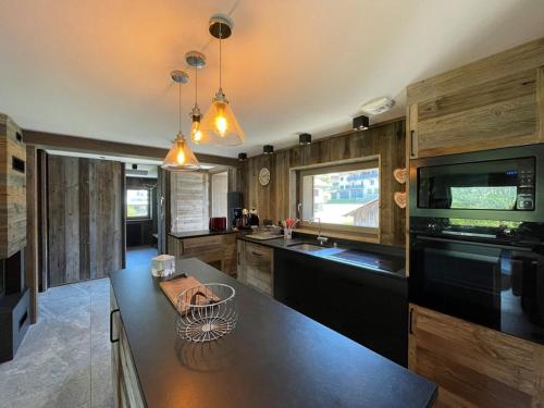 une cuisine avec des armoires en bois et un appareil noir dans l'établissement Duplex 11 pers. au centre de Crest-Voland, cheminée, ski-room, wifi, non fumeurs - FR-1-733-36, à Crest-Voland