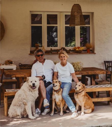a man and a woman sitting on a bench with three dogs at Giallo Limone in Teulada
