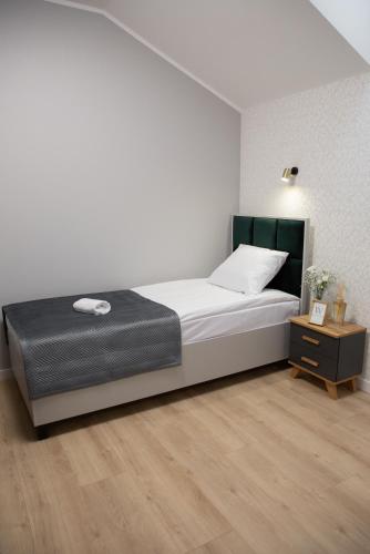 a white bedroom with a bed and a night stand at Wisteria Hotel in Laskowiec