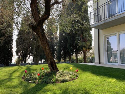 a tree in a yard with flowers in the grass at Appartamenti Villa Andrea in Garda