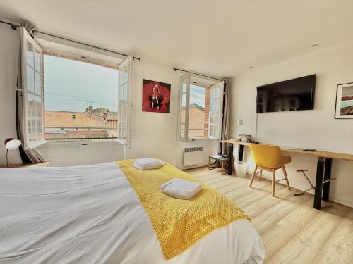 une chambre avec un lit, un bureau et une fenêtre dans l'établissement Capitole by Yumē, à Toulouse