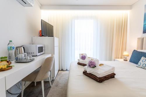 a white room with a bed and a desk with a microwave at GuestReady - Passal Guesthouse in Ponta Delgada