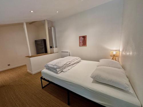 une chambre avec un lit avec des draps blancs et des oreillers dans l'établissement Appartement T3 mezzanine, plage des Sablettes à 300 m !, à La Seyne-sur-Mer