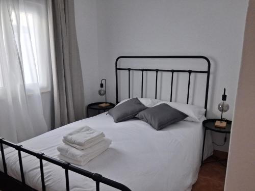 a bedroom with a bed with white sheets and pillows at Várzea Alojamentos Turísticos in Vila Nova de Milfontes