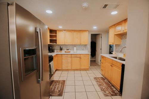 a kitchen with wooden cabinets and a stainless steel refrigerator at Cowboy Den-Hot Tub-Game Room-Pet Friendly-No Pet Fees! in Albuquerque