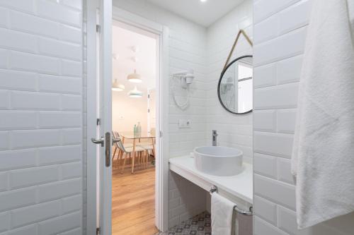 Un baño blanco con lavabo y espejo. en Cotillo Beachfront Escape, en La Oliva