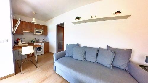 a living room with a blue couch and a kitchen at Residencial Las Dunas, Best Holiday Home Resort On The Island- VV in Corralejo