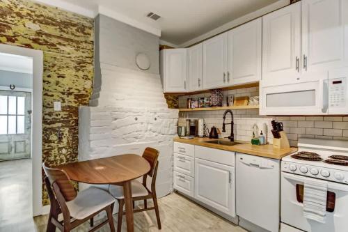 una cucina con mobili bianchi e un tavolo di legno di Hot Tub - Historic District - Next to Forsyth Park a Savannah