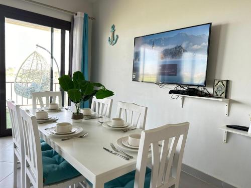 une table à manger blanche avec des chaises blanches et une télévision dans l'établissement Apartment at Marassi, à El Alamein
