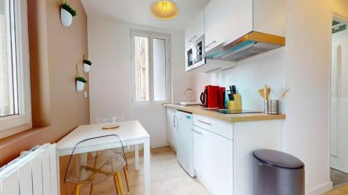 une petite cuisine blanche avec un comptoir et une table dans l'établissement Rue Guillemard Studio, au Havre