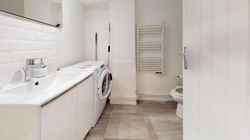 La salle de bains blanche est pourvue d'un lavabo et d'un lave-linge. dans l'établissement Rue Guillemard Studio, au Havre