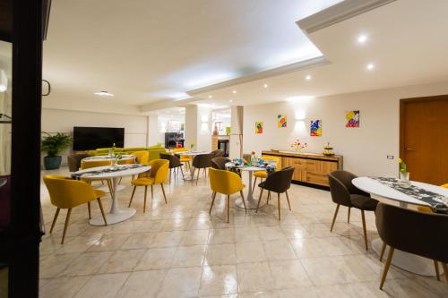 a dining room with tables and yellow chairs at Hotel Dalì in Scafati
