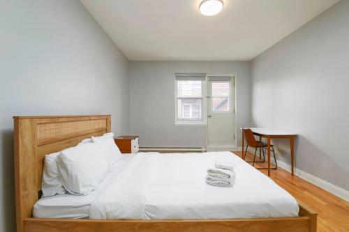 Un dormitorio con una cama con sábanas blancas y una mesa. en Awesome 2BR in Montreal, en Montreal